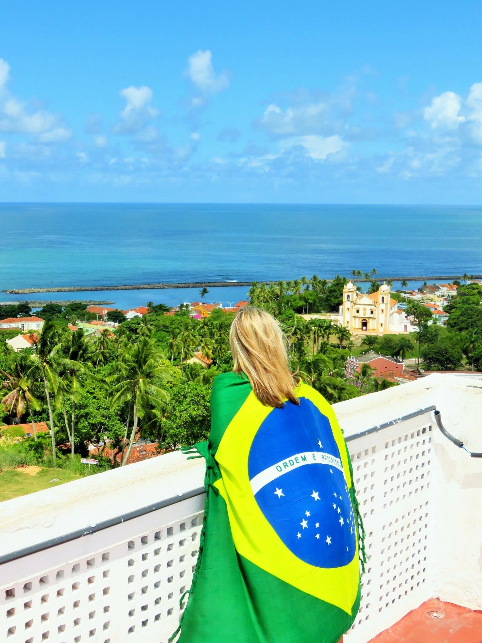 Camila overlooking Brazilian coastal town with flag